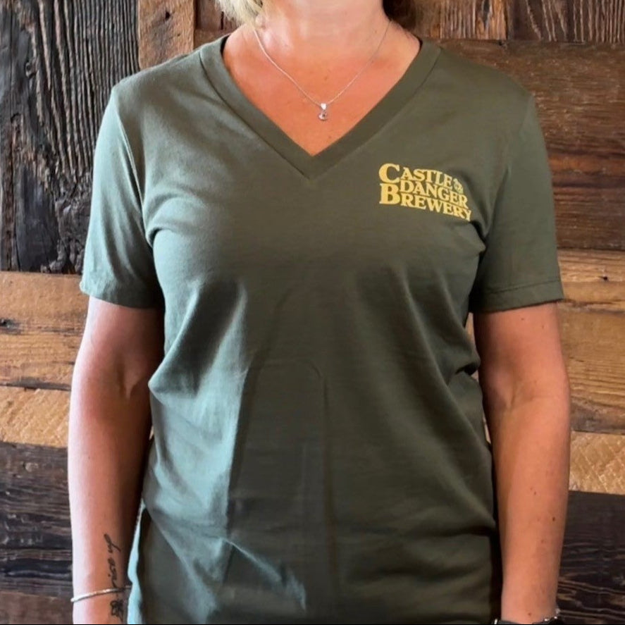 Woman wearing a green t-shirt with a logo in front of a wooden paneled wall